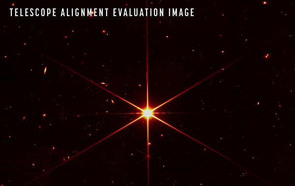 An engineering image from Webb which shows a bright star in the foreground with small galaxies and stars in the background. The bright objects in this photo are reddish, a color chosen to optimize visual contrast. Credit: NASA/STScI