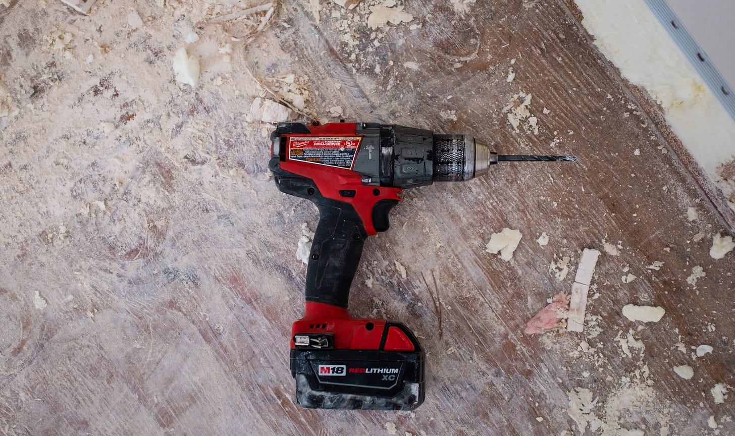 A handheld cordless electric drill on the ground of a construction site A handheld cordless electric drill on the ground of a construction site