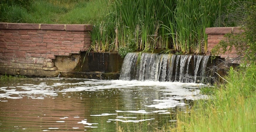Small waterfall flows into a peaceful pond.