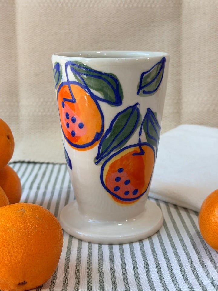 First Photo: a ceramic sundae cup with illustrated oranges.  Second photo: a round, silver ring with abalone instead of a stone