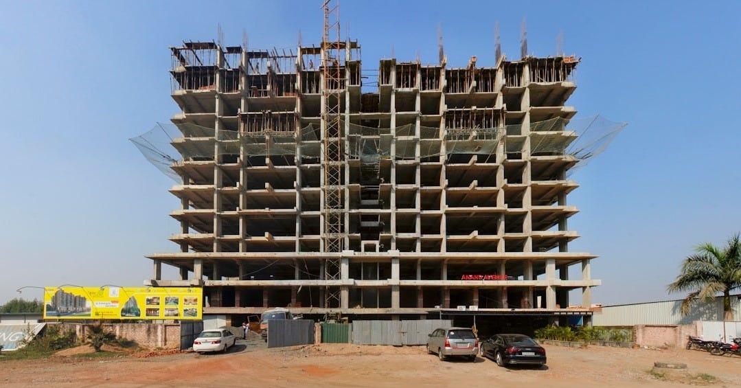 a large building under construction with cars parked in front of it