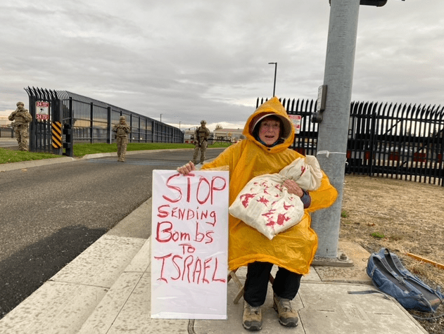 A person in a yellow raincoat holding a sign

Description automatically generated