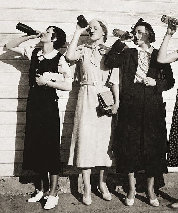 This may contain: three women standing next to each other drinking from bottles