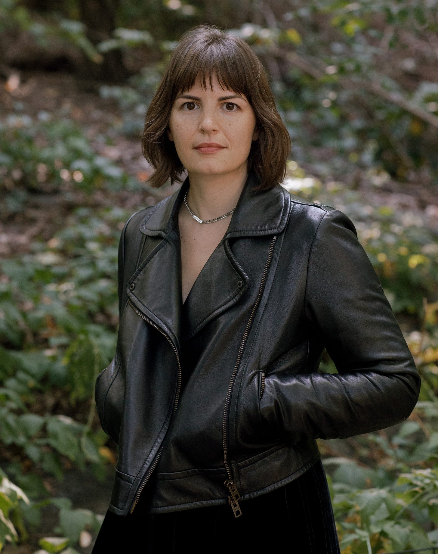 Author photo of Kerry Cullen, standing in the woods and wearing a leather jacket
