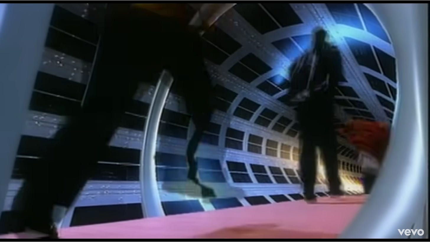 Three shadowy figures run down a space hallway; one is pretty clearly in a red jacket.