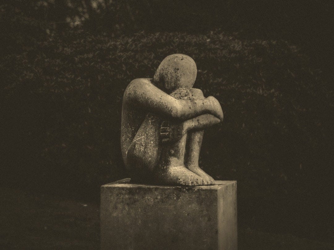 man hugging his knee statue man hugging his knee statue