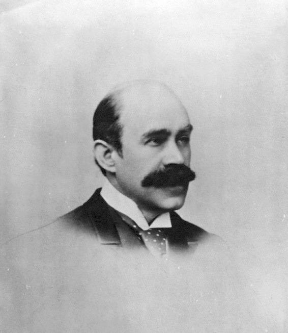 This is a photograph of Walter Pater from the shoulders up, in a ¾ pose facing the right side of the image. He is wearing a high collared shirt, wide polka-dot tie, and a dark jacket. The image fades from the top of the tie downwards.