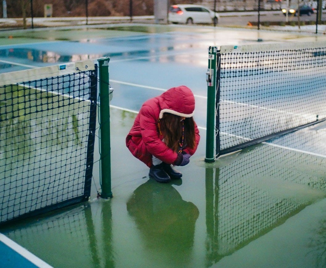 A person kneeling down on a tennis court
