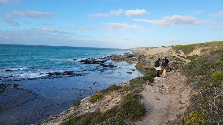 L - R: Two women hiking along a coastal path with the ocean to one side. A group of people standing on a street listening to a man speaking, while a cameraman is filming him, cloudy Table Mountain is in the background. A fireplace with lit candles in the centre, decorated with flower arrangements, other objects and photos of foremothers. Post-its and a sketch of Foregather’s creative energy model are stuck to the fireplace.