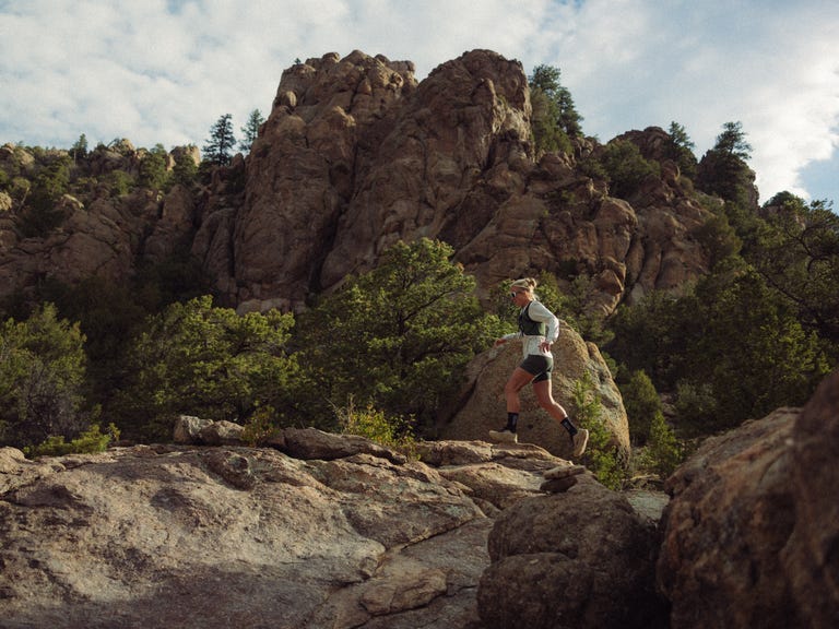 Runner navigating rocky terrain surrounded by trees and mountains on a cloudy day. Runner navigating rocky terrain surrounded by trees and mountains on a cloudy day.