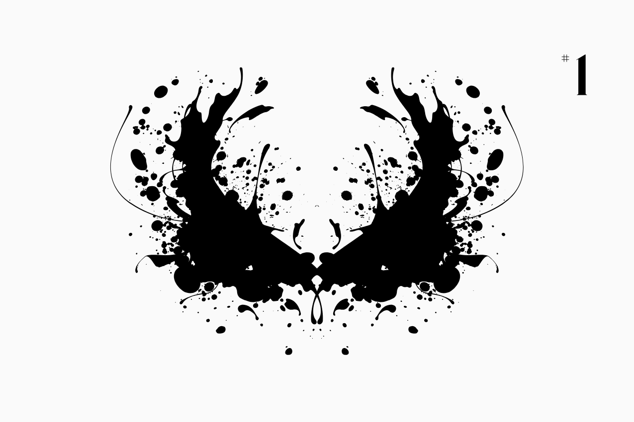 A bilateral, Rorschach-style inkblot specimen for the “In Other Words” series from The Subtext Review. The charcoal-black symmetrical splatter is centered on a cream paper background, labeled as Puzzle No. 1 in a classic serif typeface.