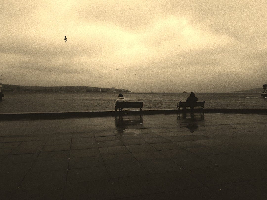 grayscale photo of person sitting on bench