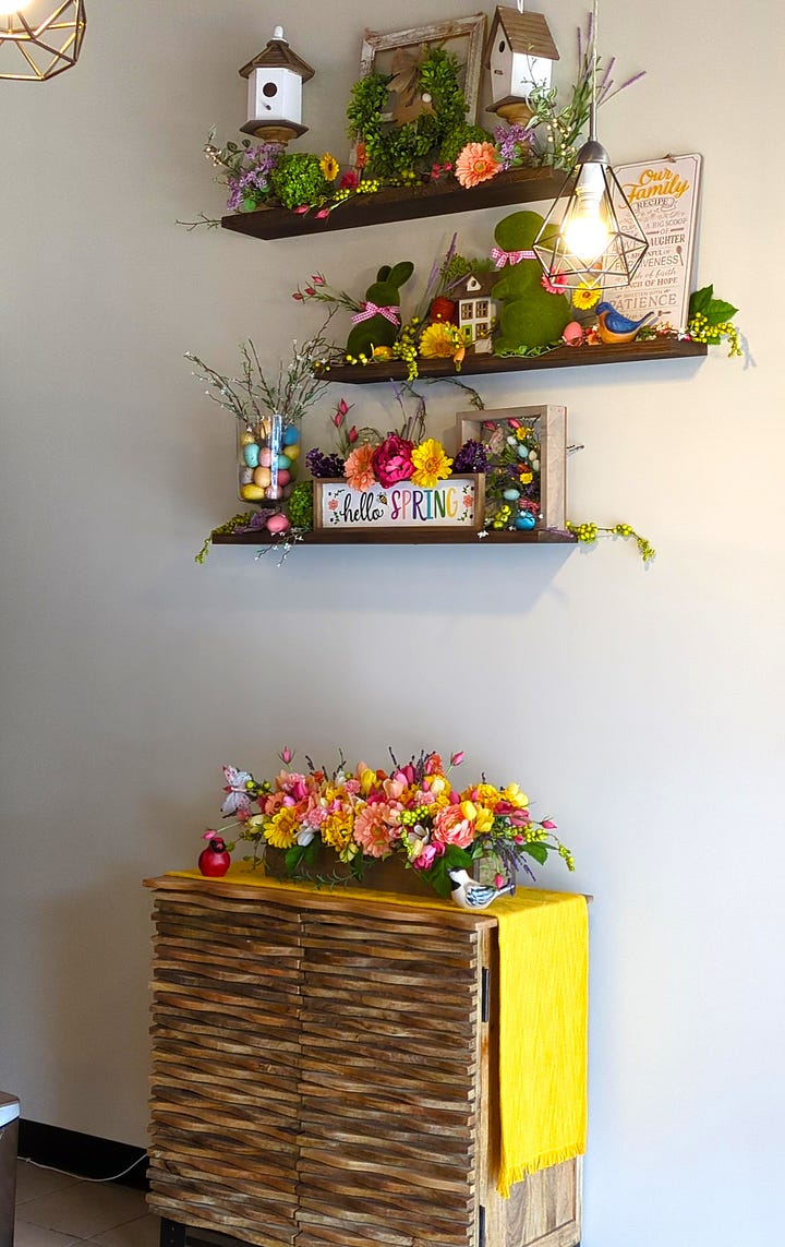 Interior shots include a Lego Starry Night piece on the counter next to a sign that reads, "The secret ingredient is always love." The next photo is of the cooler with some of the food available that night. Next is a stand full of hot cocoa mix jars. Also, she has a corner with seasonal decor that is always super cute. Lastly, there's a display rack with food from other local vendors like honey.