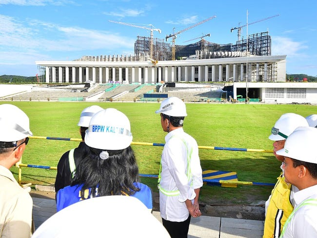 Un palais mégalomane en construction face à son futur locataire, en visite sur le chantier, casque sur la tête Un palais mégalomane en construction face à son futur locataire, en visite sur le chantier, casque sur la tête