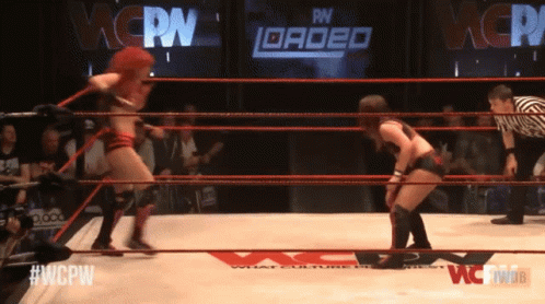 two women wrestling in a ring with a sign that says wcpn