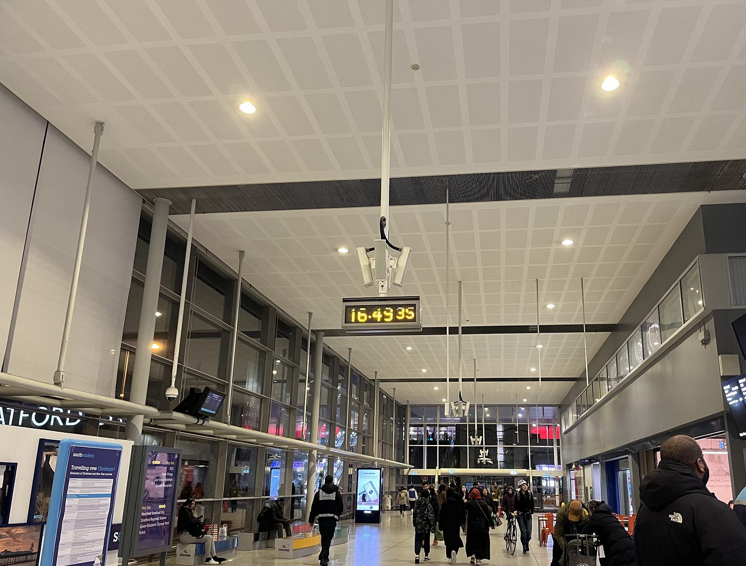 Photo showing ceiling mounted digital clock in station, with hours, minutes and seconds visible. The camera has struggled to capture the screen perfectly.