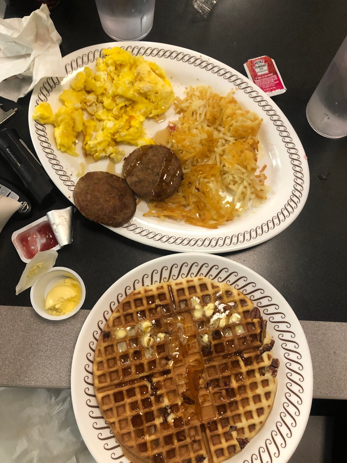 an image of waffle house's all star special with a pecan waffle, two sausage patties, hashbrowns spread between two plates and taken from above.