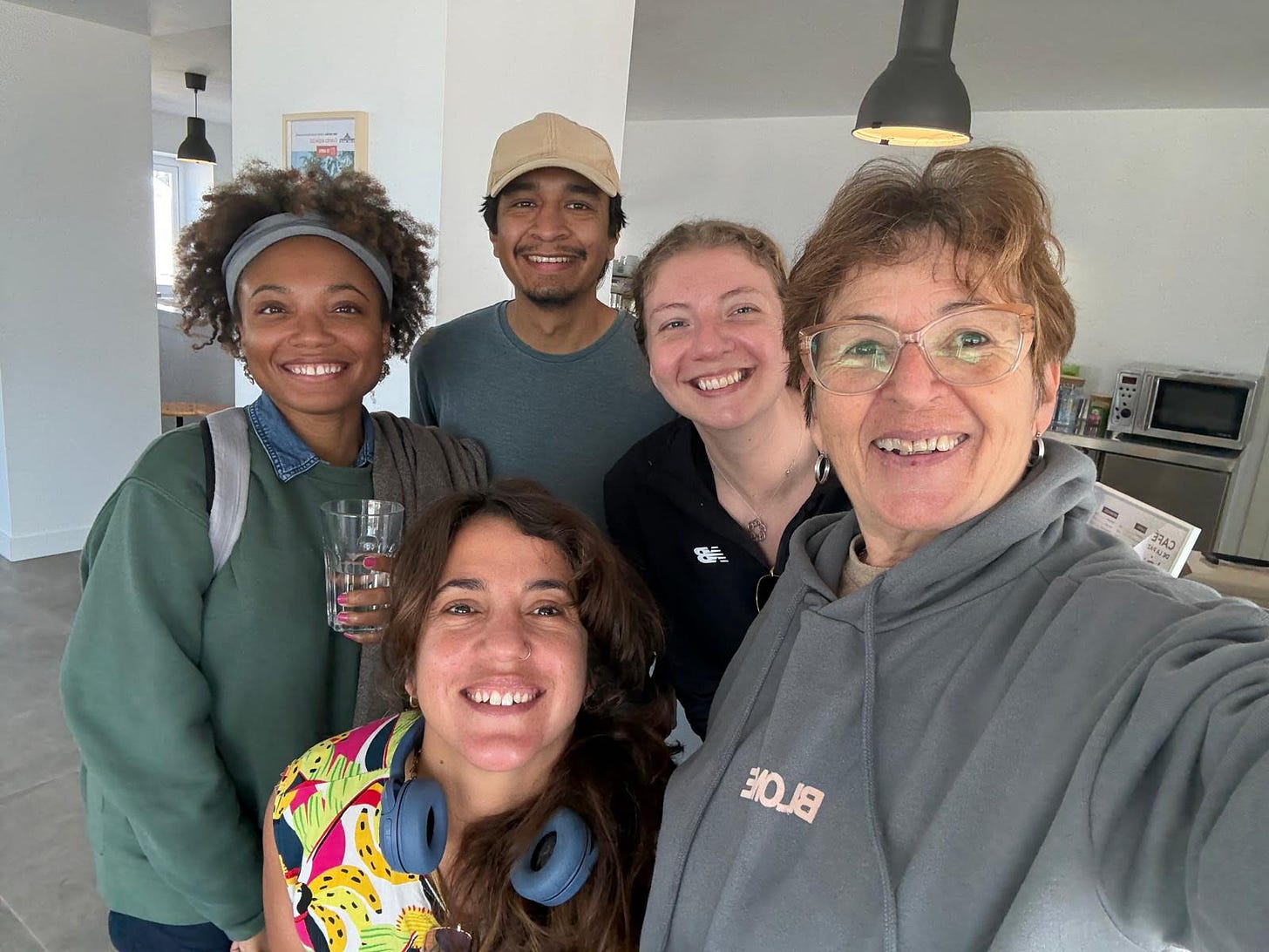Five volunteers smiling together in the communal kitchen area of the meditation center. Five volunteers smiling together in the communal kitchen area of the meditation center.