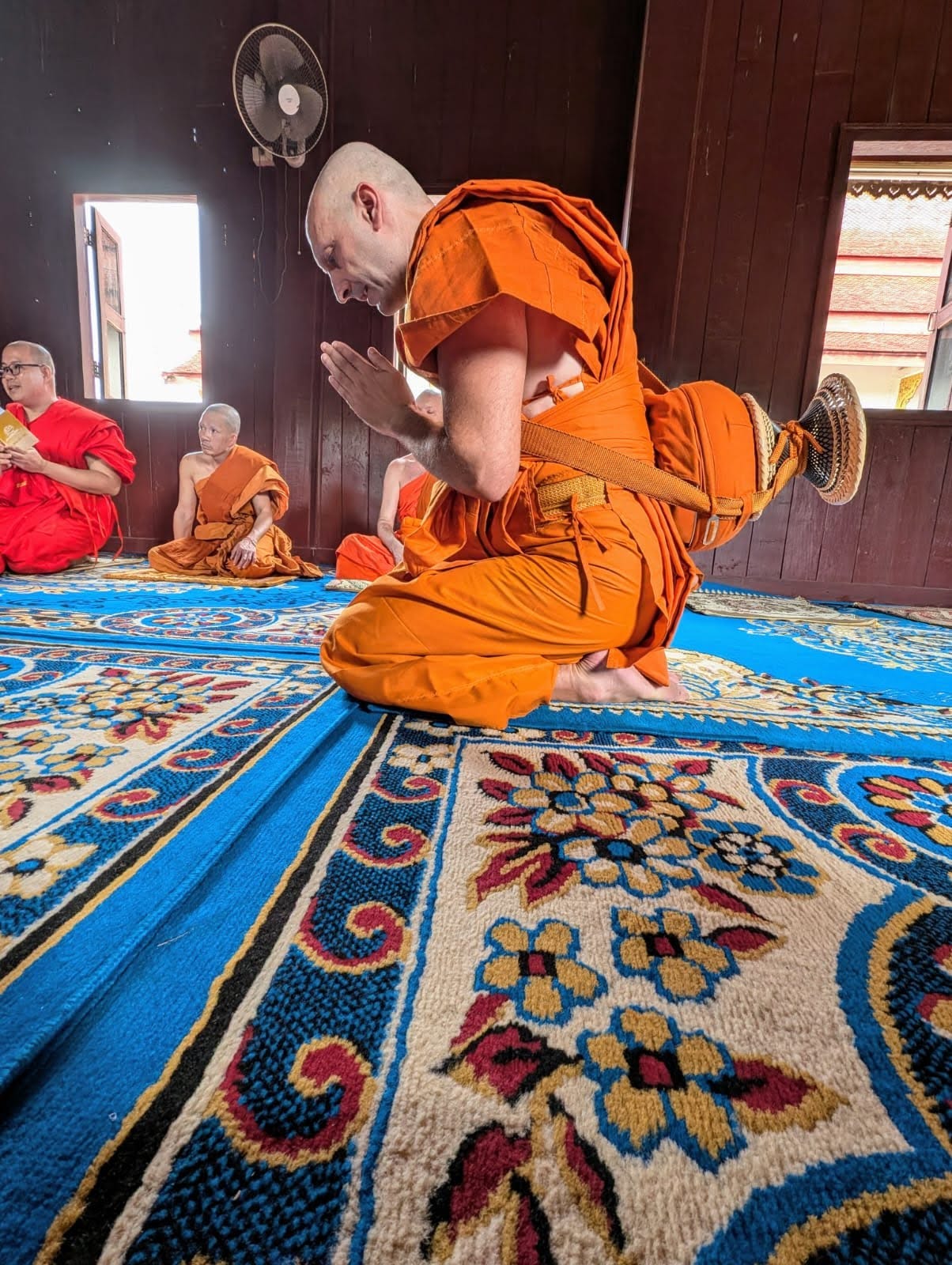 Monk sitting on knees head down in a temple chanting
