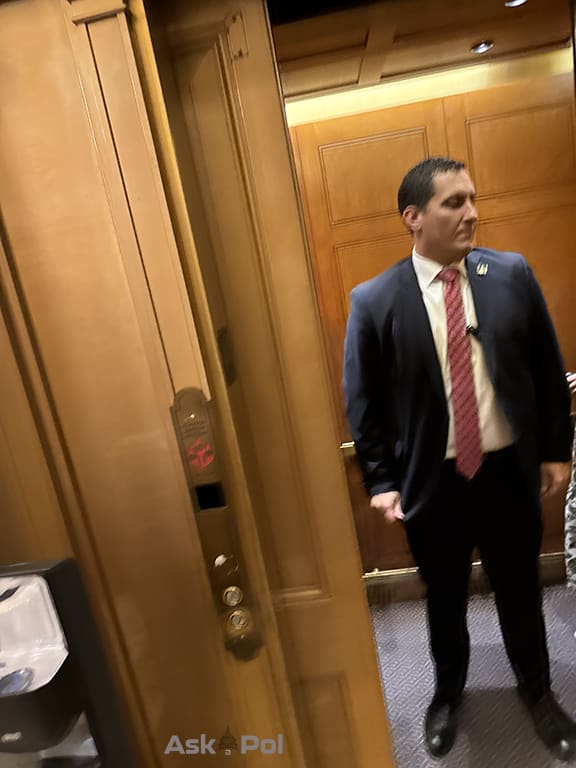 Security guard in tie and suit waits for elevator door to close. Photo © wwwaskapol.com