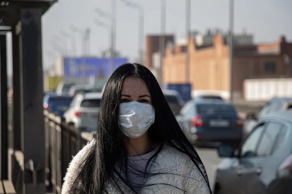 A generic photo of a woman walking down a street wearing a facemask for protection