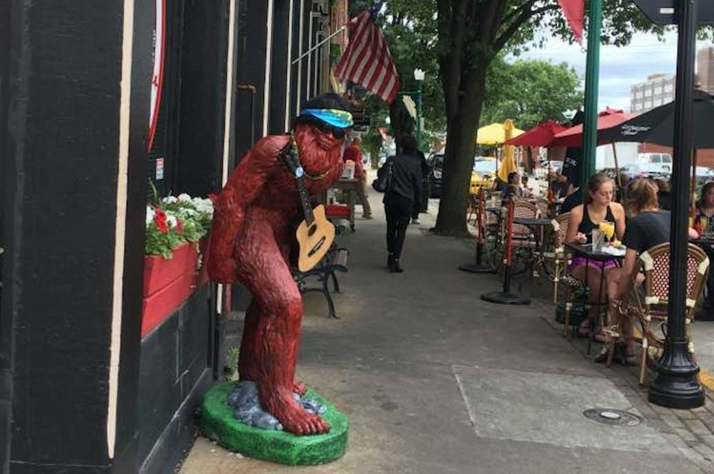 a person in a garment playing a saxophone on a sidewalk a person in a garment playing a saxophone on a sidewalk