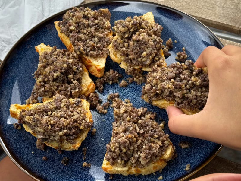 A hand reaches for some haggis on toast A hand reaches for some haggis on toast