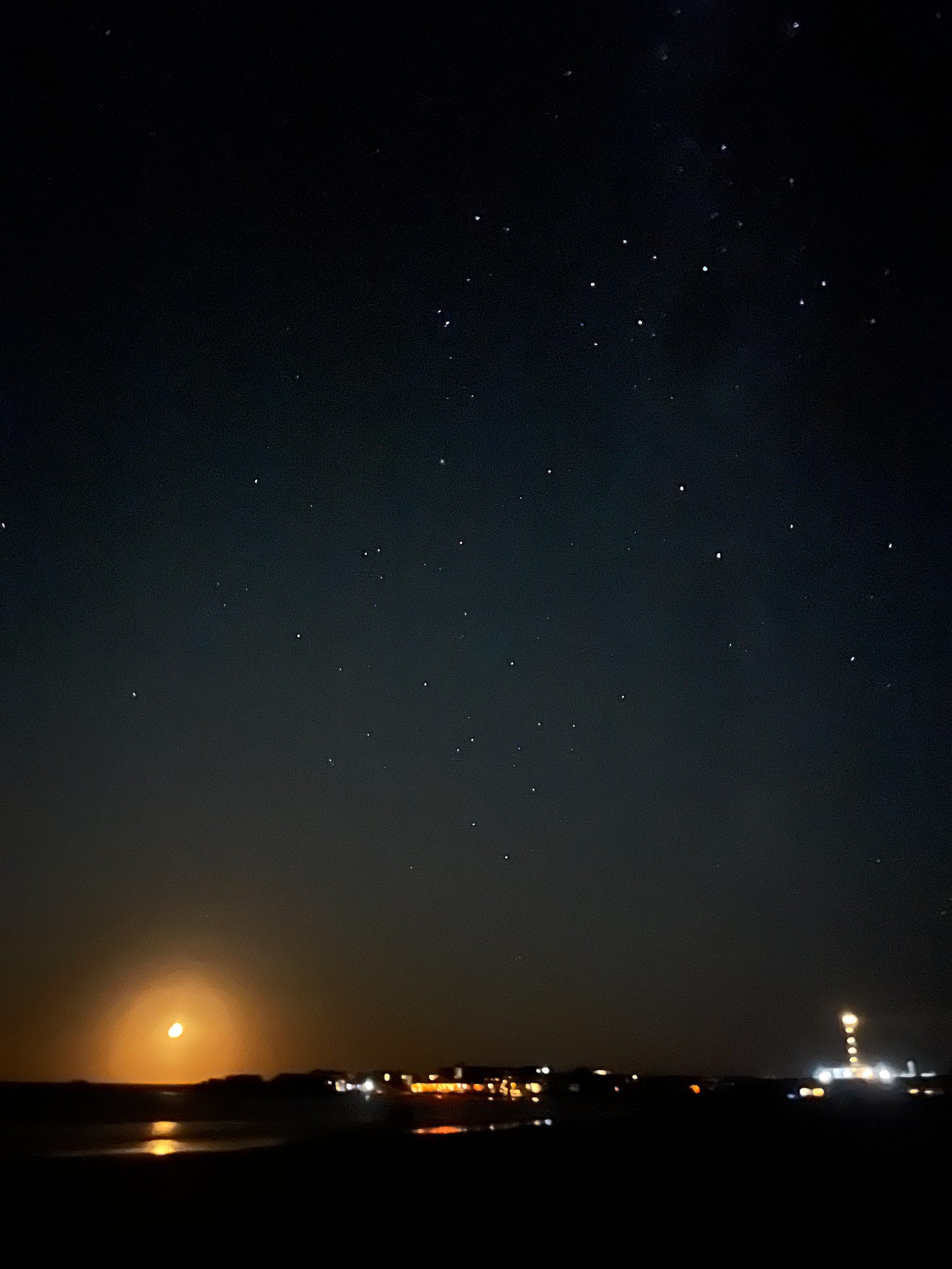 a black sky filled with many bright stars and the light of a lighthouse in cabo polonio