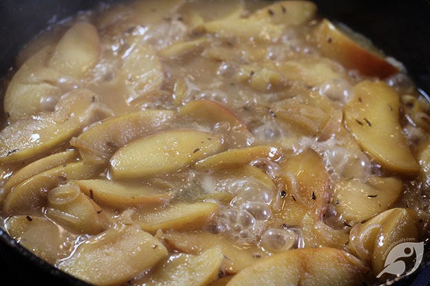 apples and shallots cooking in a cast iron skillet with chicken stoc and mustard apples and shallots cooking in a cast iron skillet with chicken stoc and mustard