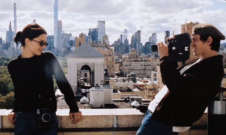 This may contain: two people standing on top of a building taking pictures