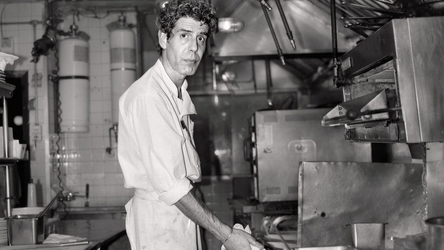 A younger Anthony Bourdain cooking in a kitchen.