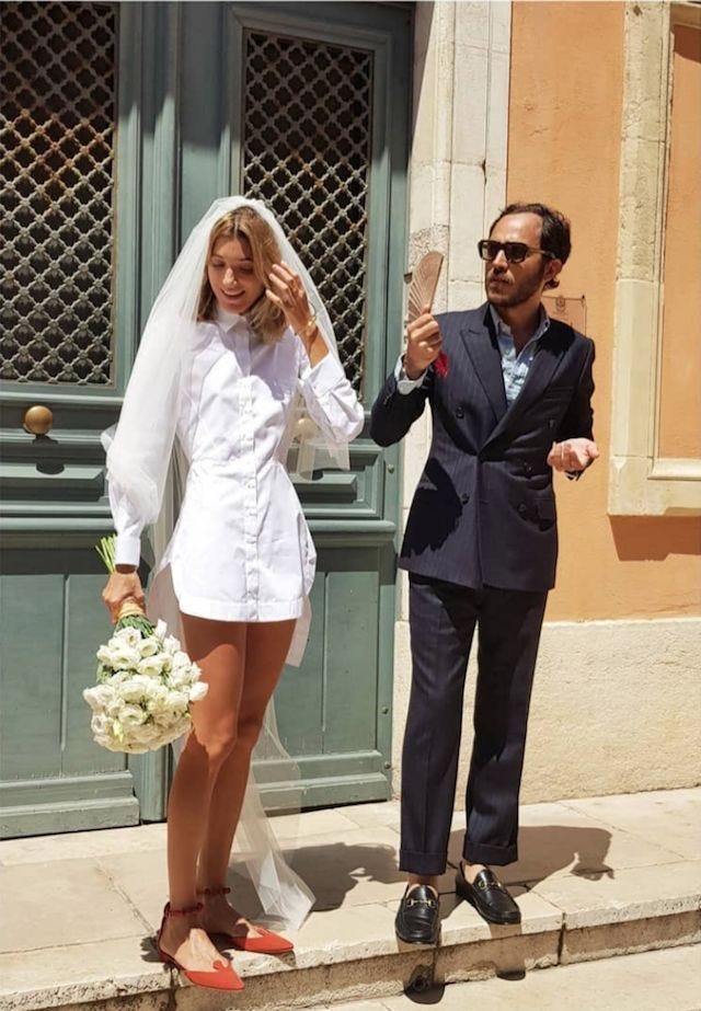 This may contain: a man and woman dressed in wedding attire standing on the steps with their hands together This may contain: a man and woman dressed in wedding attire standing on the steps with their hands together