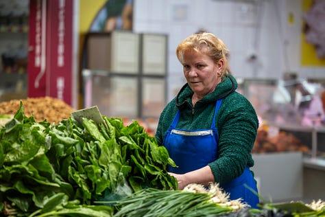 Această galerie se oprește asupra oamenilor din piață: vânzători, legumicultori, femei și bărbați pentru care taraba nu este doar loc de lucru, ci rezultatul unei munci duse luni întregi. Ridurile, privirile, gesturile și răbdarea lor spun o poveste despre efort, continuitate și legătura directă dintre pământ și oraș.