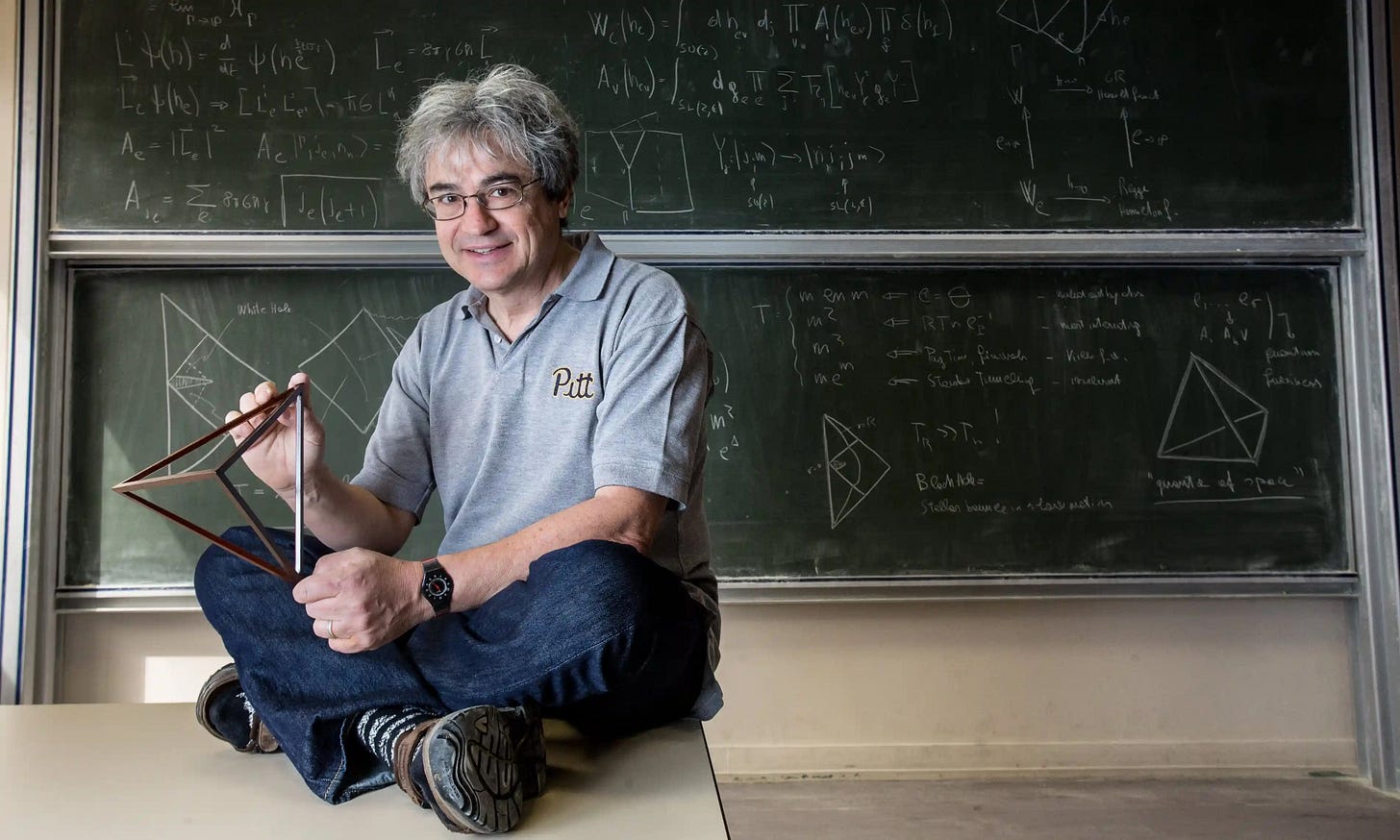 Carlo Rovelli sitting in front of a blackboard