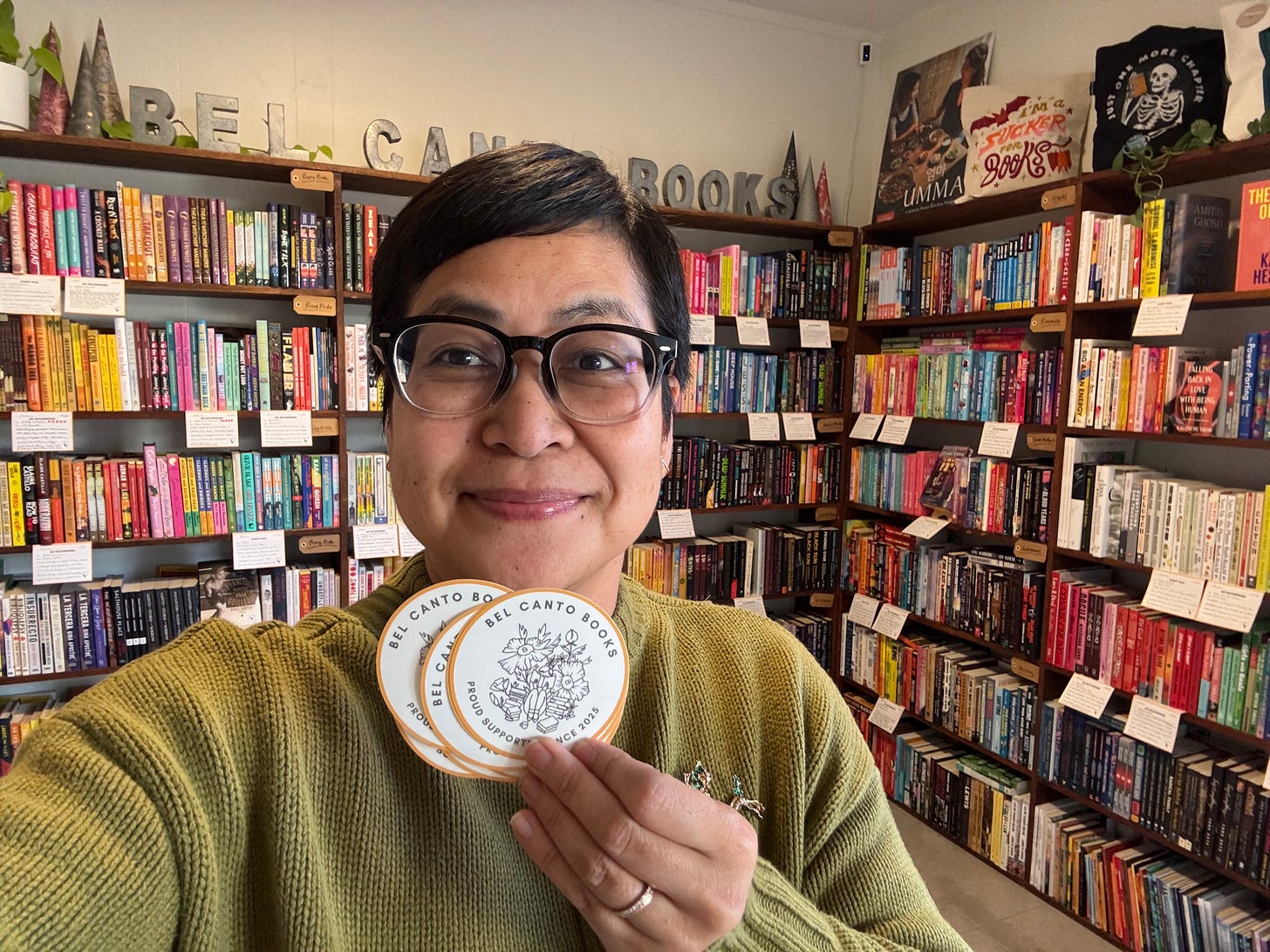 Jho holding BCB supporters stickers with BCB bookcase in the background