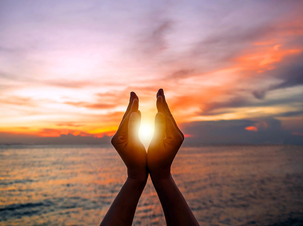 Hands framing the sun on summer solstice. 