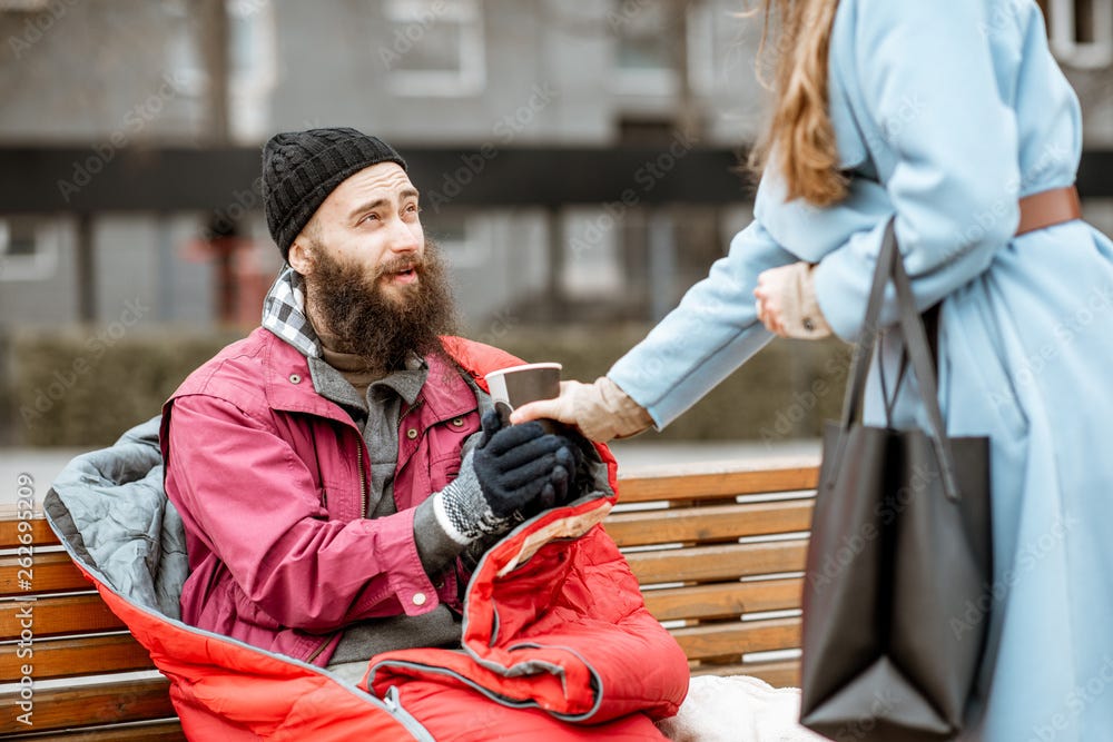 Woman helping homeless beggar giving some hot drink outdoors. Concept ...