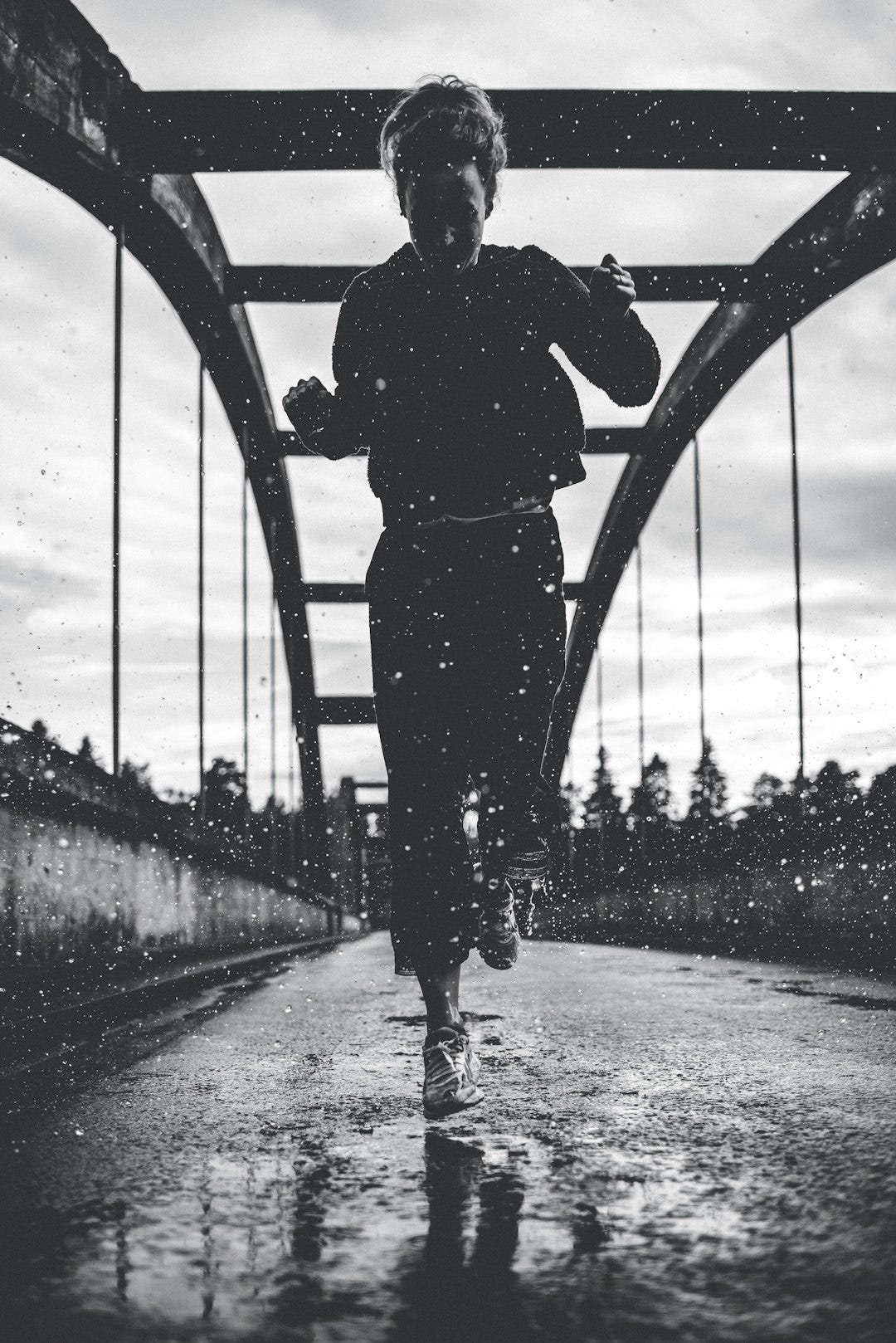 greyscale photography of woman running on bridge greyscale photography of woman running on bridge