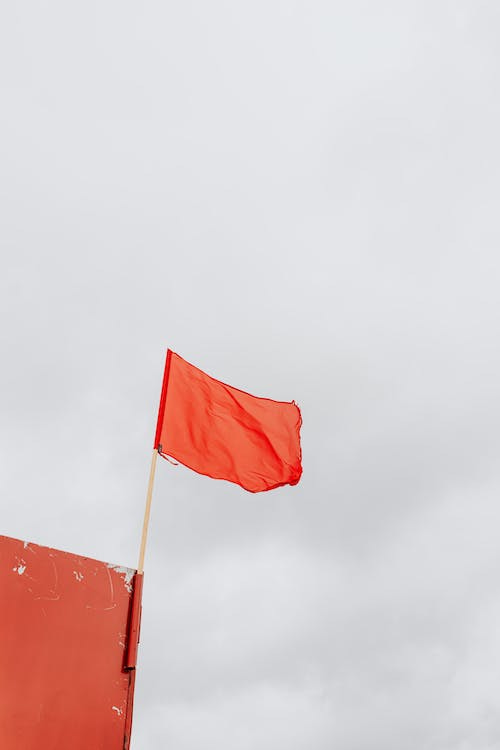 Free Red Flag on Pole Swaying by the Wind Stock Photo