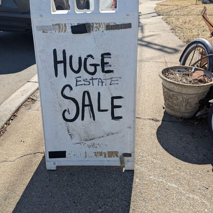 This may contain: a sign that says huge estate sale on the side of the road next to a bicycle