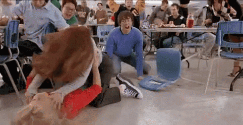 a group of people are fighting in a cafeteria while tables and chairs are destroyed . a group of people are fighting in a cafeteria while tables and chairs are destroyed .