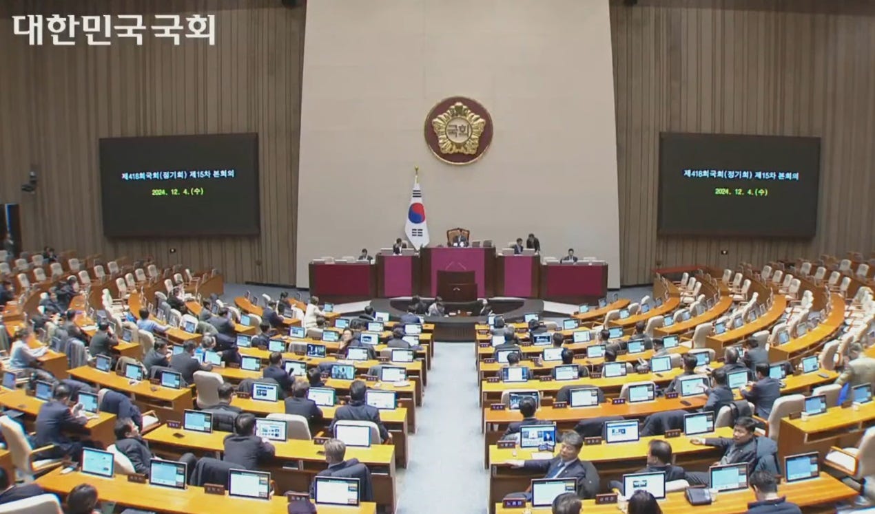 video screenshot of parliament chamber, a hall with legislators's desks and computer terminals arranged in concentric semicircles. video screenshot of parliament chamber, a hall with legislators's desks and computer terminals arranged in concentric semicircles.