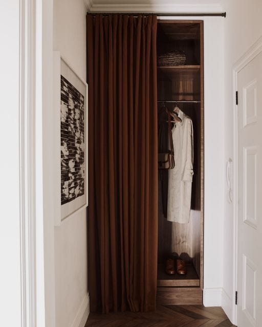 This may contain: an open closet with clothes hanging on the door and a pair of shoes in it This may contain: an open closet with clothes hanging on the door and a pair of shoes in it