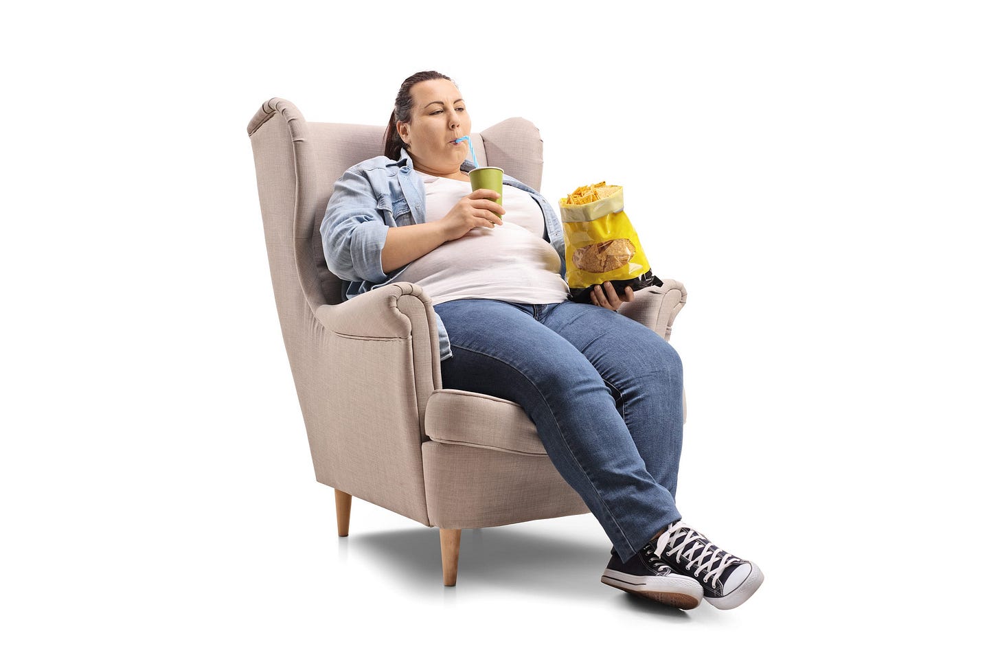overweight woman in an armchair drinking soda and eating chips overweight woman in an armchair drinking soda and eating chips