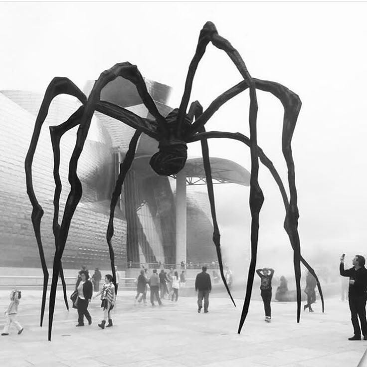 This may contain: a giant spider sculpture in front of a building with people standing around it and looking at it