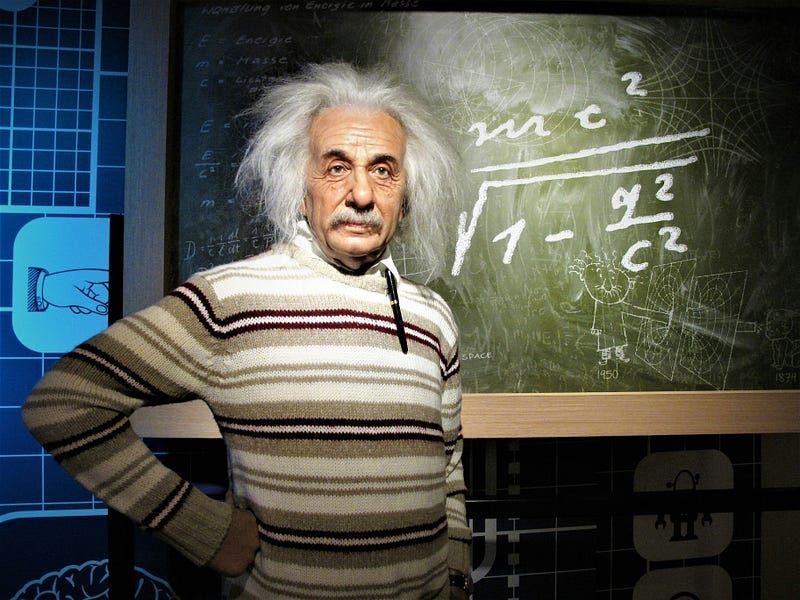Albert Einstein near a blackboard in a classroom,