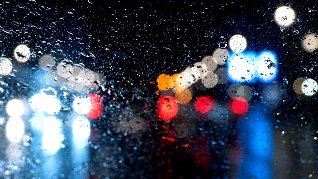 Raindrops on window with blurred city lights at night Raindrops on window with blurred city lights at night