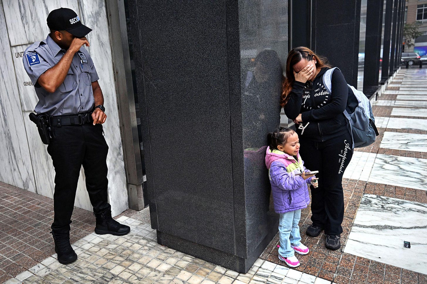 After her husband was detained by ICE agents on Aug. 20, a woman with her child wept outside a federal building in New York City; a security guard was moved to tears as well. There was no word at the time on if the detained man faced any criminal charges. By Carol Guzy After her husband was detained by ICE agents on Aug. 20, a woman with her child wept outside a federal building in New York City; a security guard was moved to tears as well. There was no word at the time on if the detained man faced any criminal charges. By Carol Guzy