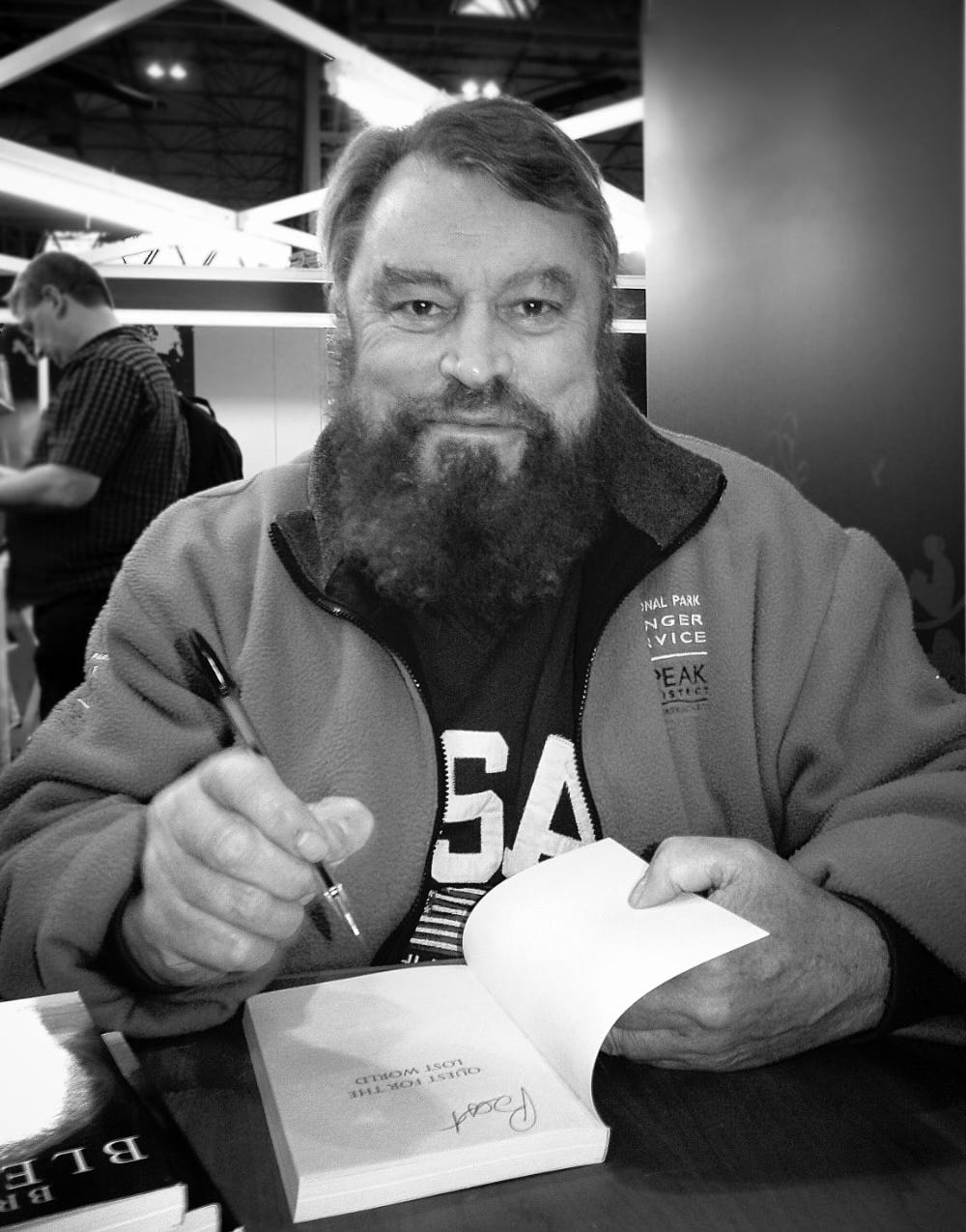 A photo of Brian Blessed signing a book for me at an event in London. He is looking at me and smiling after calling me a lucky bastard.