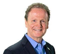 A person in a suit smiling

Description automatically generated